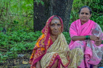 Portrait of senior women sitting against trees outdoors