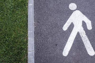 White pedestrian figure walking towards the edge on the road, bordering on a garden. conceptual idea