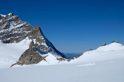 Scenic view of snowcapped mountains against clear blue sky