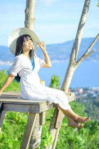 Portrait of young woman looking away while sit on hill