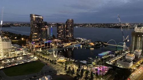 High angle view of illuminated buildings by river against sky