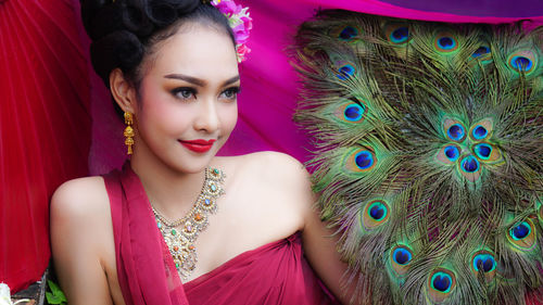 Close-up beautiful young woman with peacock feathers