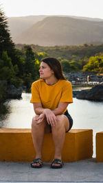 Young woman looking at lake against mountain