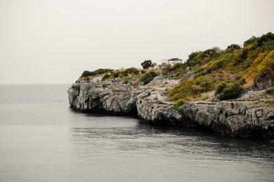 Rock formations by sea against clear sky