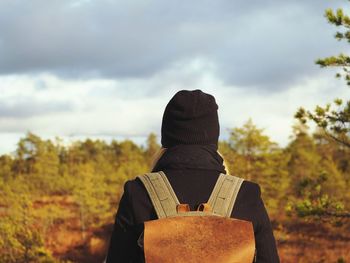 Rear view of woman standing against cloudy sky