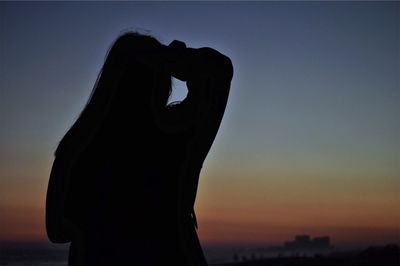 Close-up of silhouette person against sea during sunset