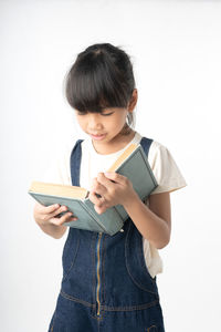 Young woman reading book against white background