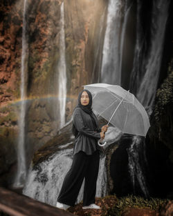 Girl standing by waterfall in forest