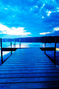 Wooden pier on lake against cloudy sky