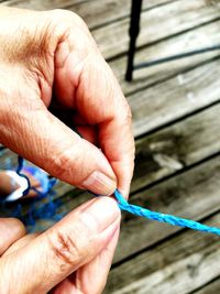 Cropped image of person braiding blue strings