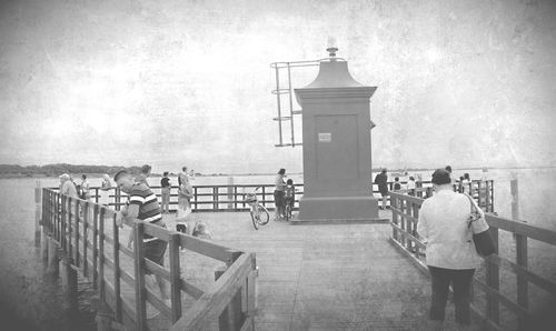 Rear view of people walking on railing against sky