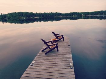 Pier on lake against sky during sunset