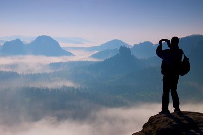 Man photographing on mountain against sky