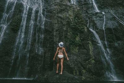 Woman standing by rock formation in forest