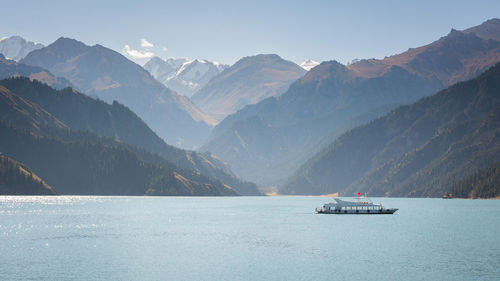 Boat sailing on sea by mountains against sky