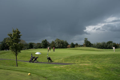 People playing soccer on golf course against sky