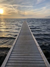Pier over sea against sky during sunset