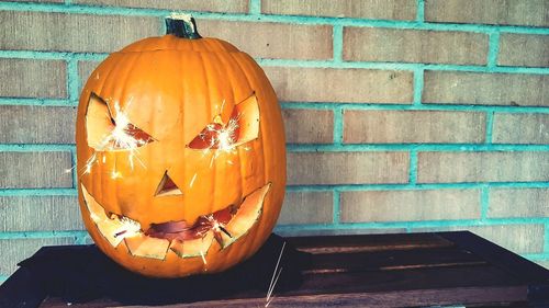 Close-up of pumpkin against orange wall during halloween