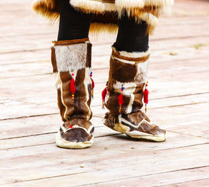 Low section of person wearing boot standing on wooden floor