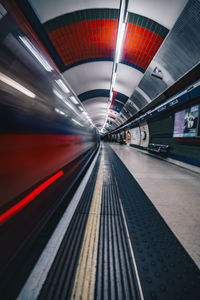 Blurred motion of train at illuminated subway station platform