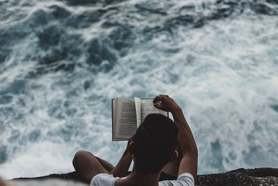 High angle view of cropped man reading book