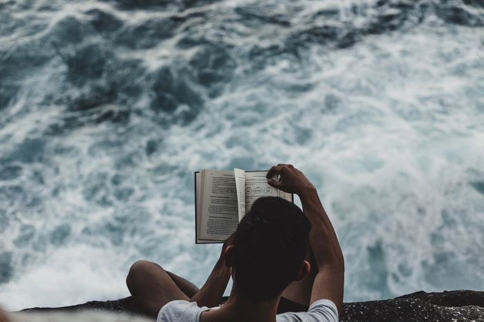 High angle view of cropped man reading book