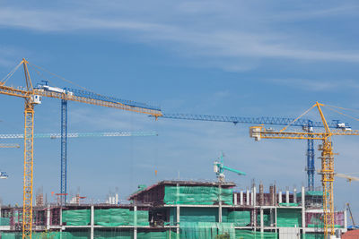 Cranes at construction site against sky