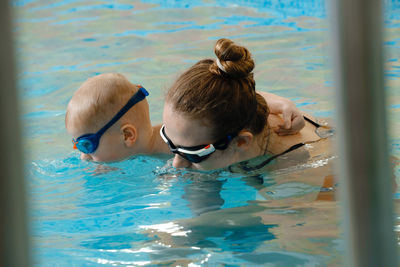 Toddler child learning to dive in indoor swimming pool with teacher. in the water