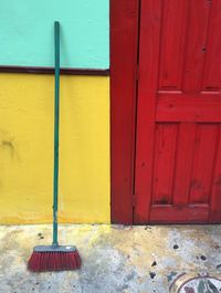 Broom leaning on wall by closed door