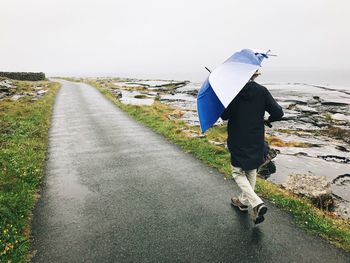 Rear view of man standing on road against sky