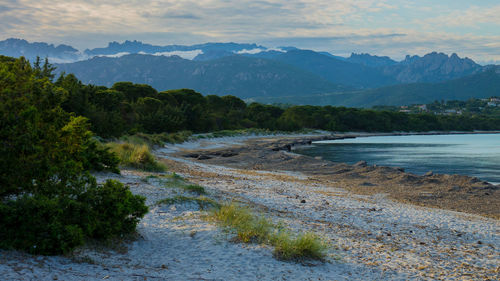 Scenic view of river by mountains against sky