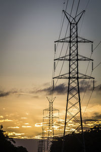 Low angle view of silhouette electricity pylon against sky during sunset