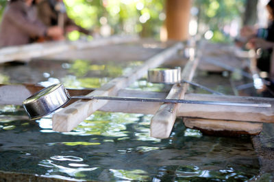 Close-up of water fountain with metallic ladles at yasukuni shrine