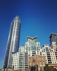 Low angle view of modern buildings against blue sky