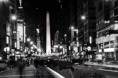 Illuminated street amidst buildings in city at night