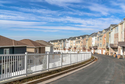 Street by buildings in city against sky