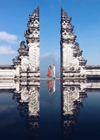 Reflection of clock tower on water against sky