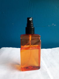 Close-up of orange bottle on table against wall