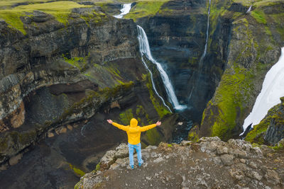 Man standing on rock by waterfall