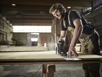 Carpenter sawing wood with handsaw