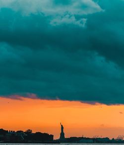 Silhouette of statue against cloudy sky during sunset