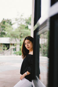 Portrait of smiling young woman standing by window