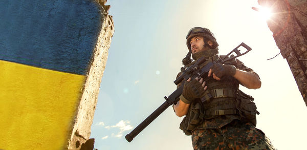 Ukrainian soldier military in the war with a weapon in his hands. the flag of ukraine is painted on