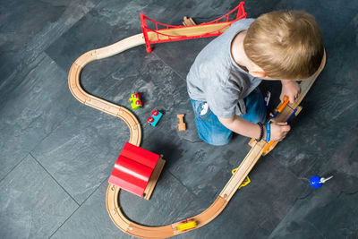 High angle view of boy playing with miniature train at home