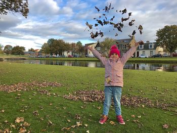 Boy standing by leaves on field against sky