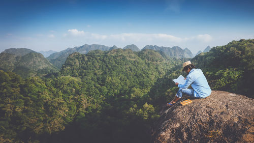 Side view of man standing on mountain against sky