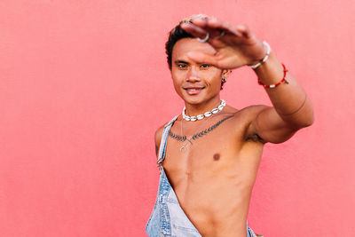 Smiling man gesturing against pink wall