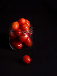 Close-up of tomatoes in glass jar on table against black background