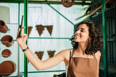 Female potter entrepreneur taking selfie in mobile phone in pottery shop