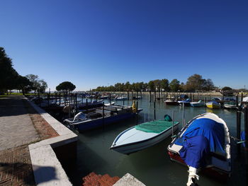 Boats moored in lake against clear blue sky